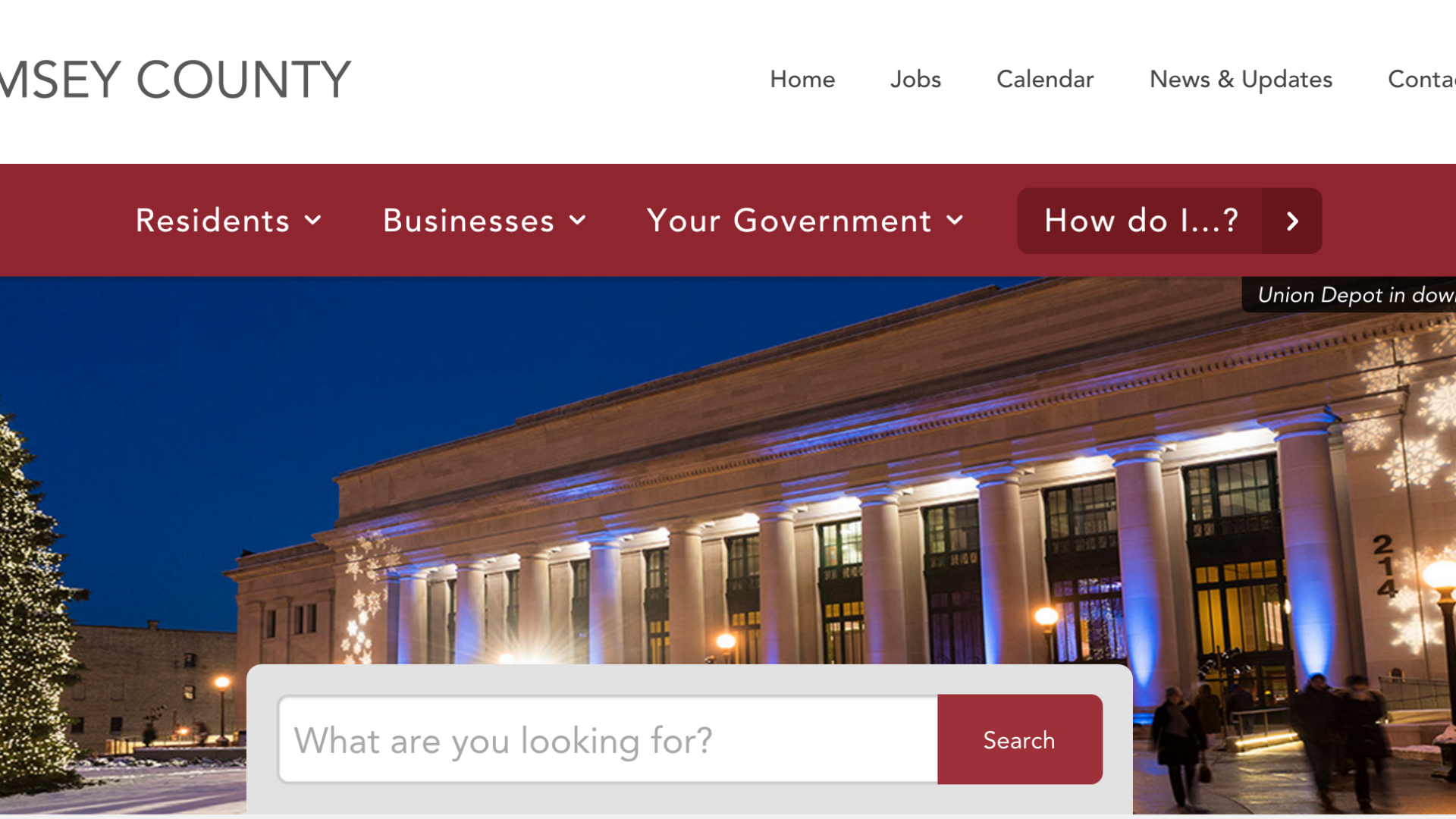 A screenshot of the Ramsey County website homepage showcases its digital solution. The header features navigation links and a search bar. A winter scene in downtown Saint Paul displays a lit-up building, a Christmas tree, and snowflake decorations at night.