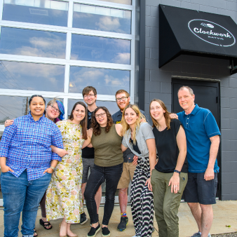 A group shot of Clockwork employees posing in front of the Rayvic Clockwork headquarters