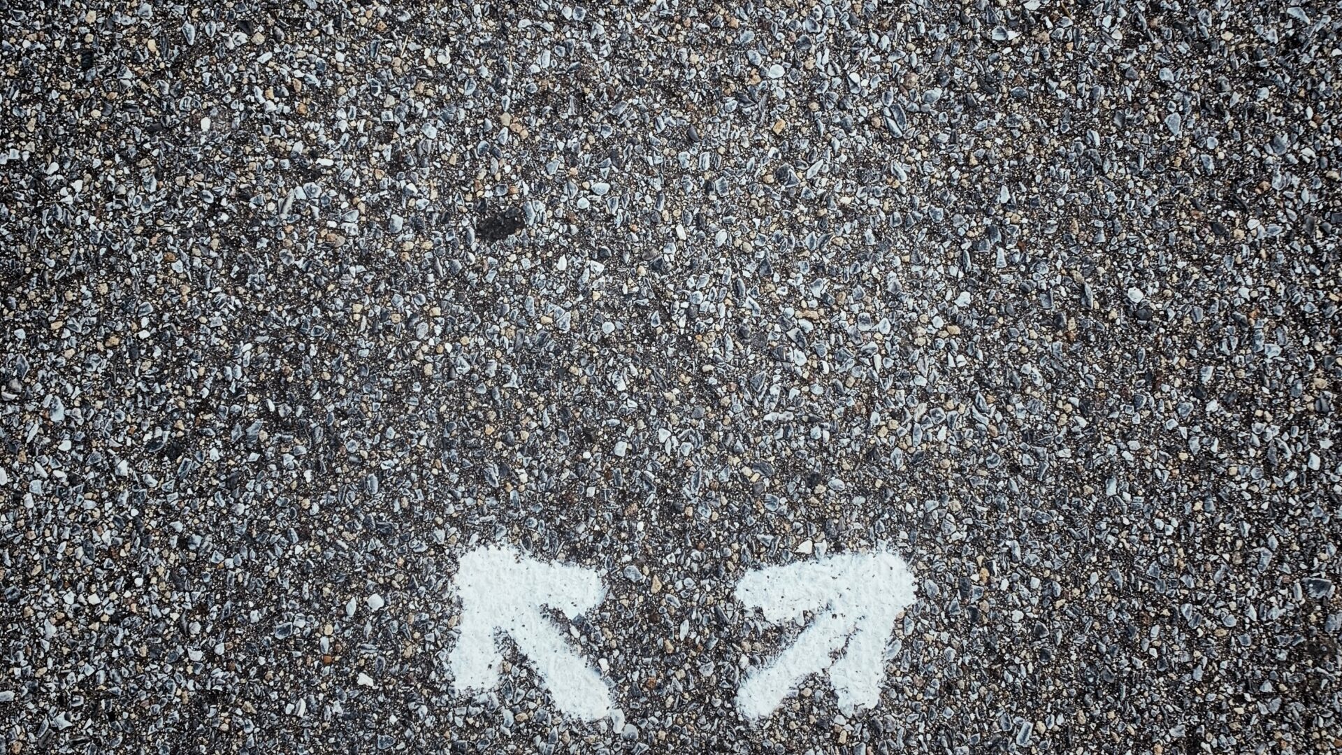 A pair of black shoes stands on asphalt, flanked by two white arrows pointing in different directions. This scene resembles a clockwork of choices, embodying the essence of experience design.