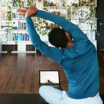 person seated on a yoga mat stretching while practicing wellness