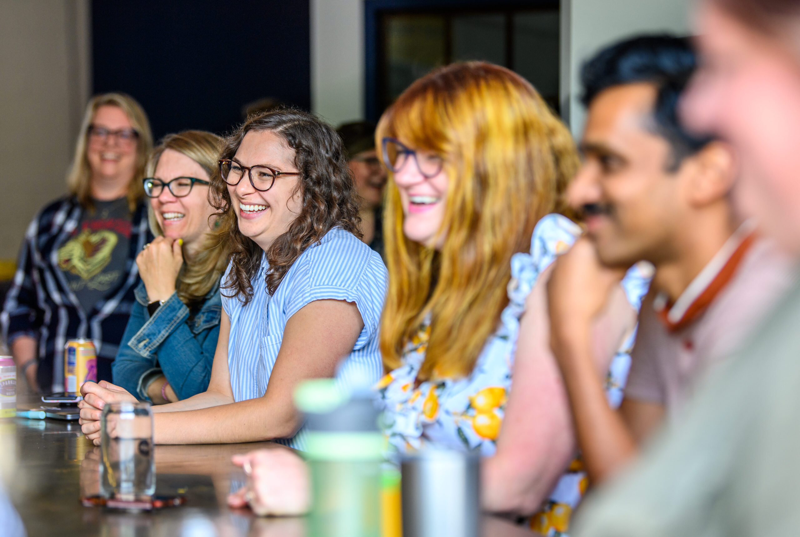 A row of smiling Clockworkers sitting at our Rayvic kitchen table