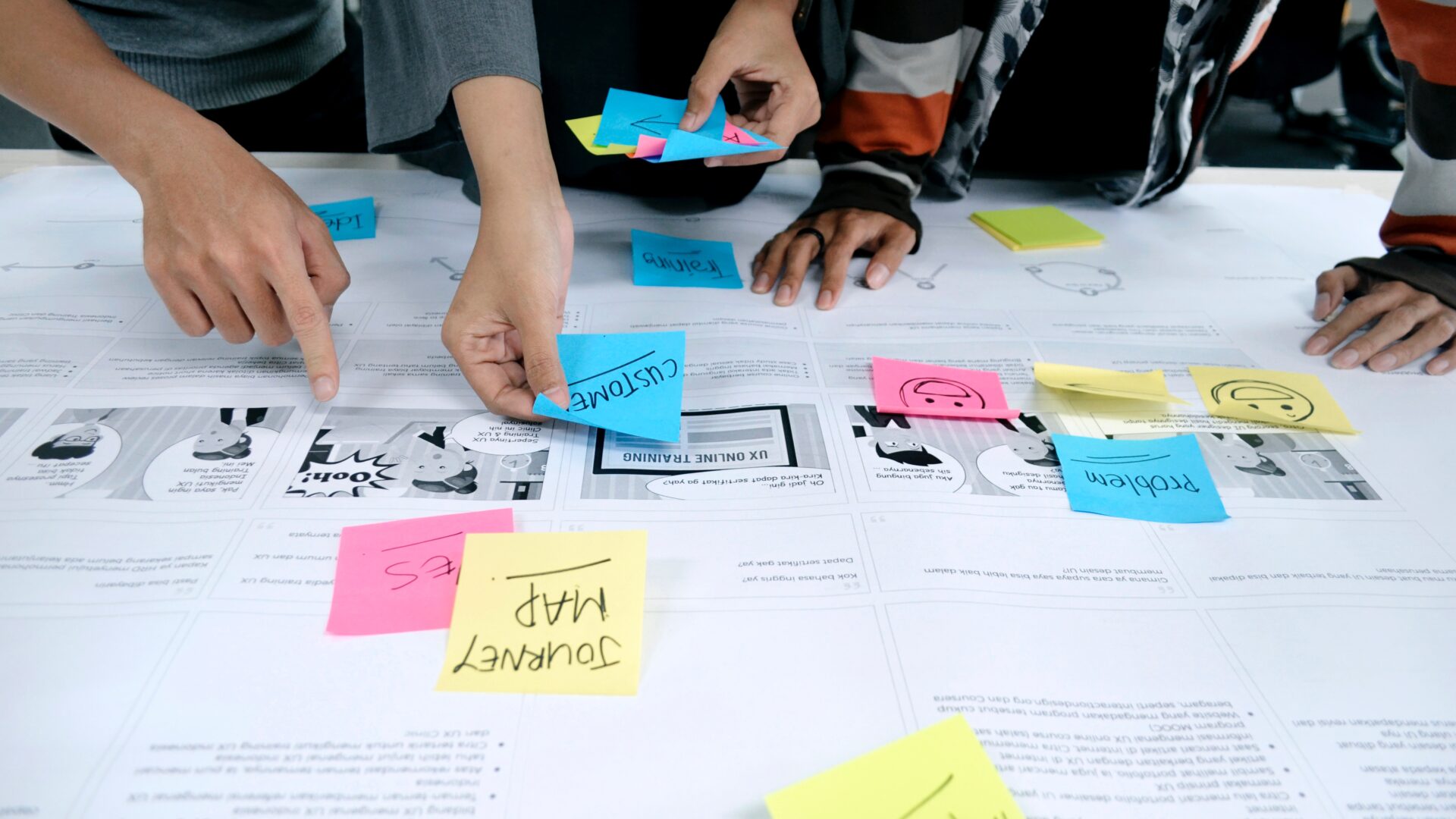hands mapping customer behavior using strategic thinking and post-its