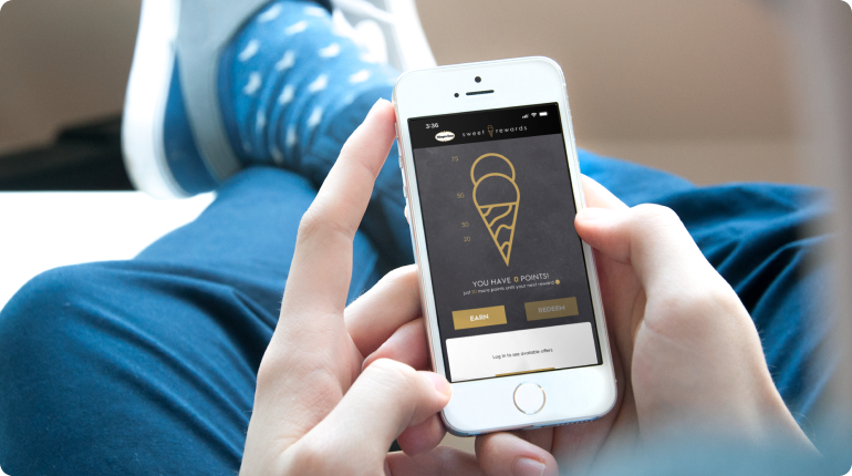 person holding a mobile phone viewing the automated reporting app for haagen dazs franchise owners