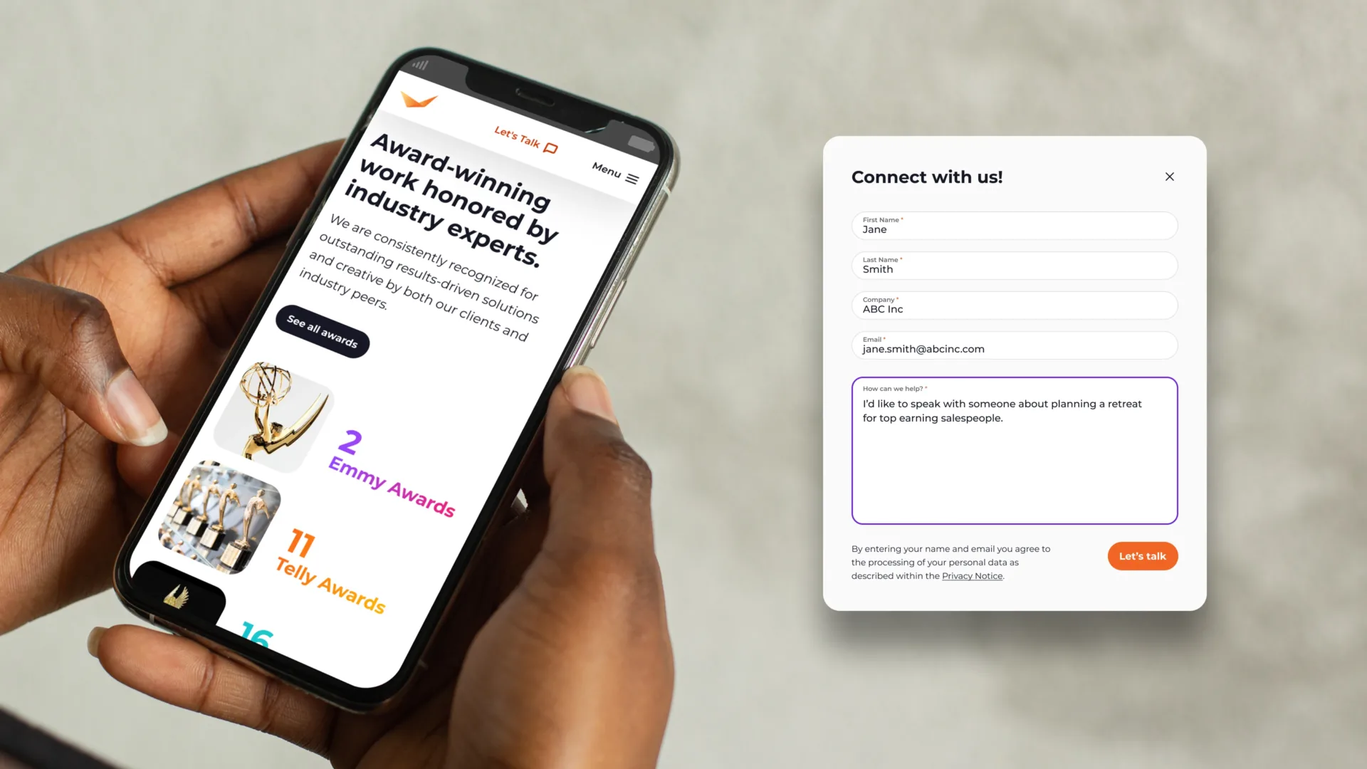 A person holds a smartphone displaying an awards page with Emmy and Telly Award counts from the company’s global website. Next to it, a contact form appears on a light background, inviting users to connect with the company.