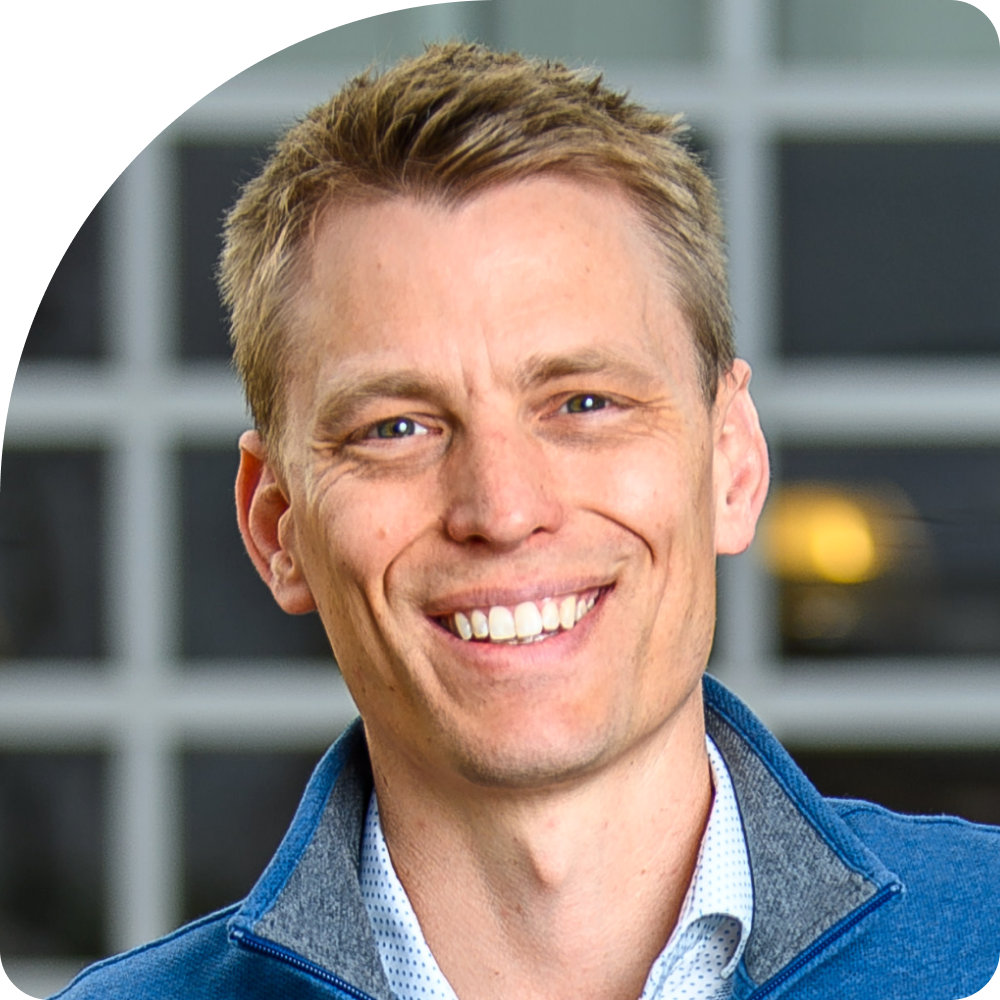Luke Vestrum, Managing Director of Tempo. A smiling man with short light brown hair, wearing a blue jacket over a white shirt, stands in front of a blurred background with grid-like windows.